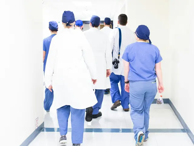 A care team in scrubs and white coats walking down a corridor